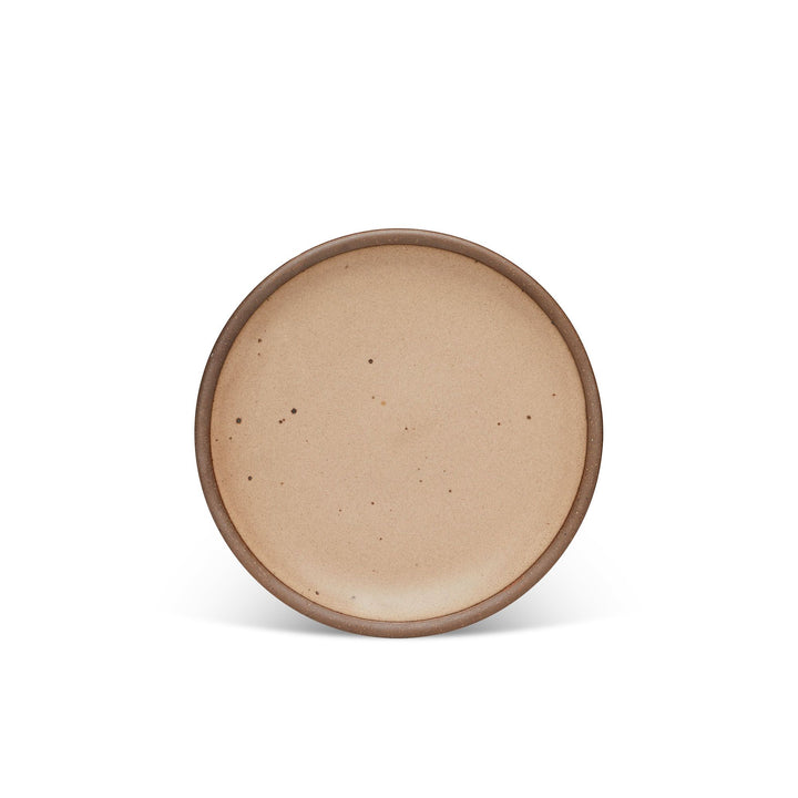A medium sized ceramic plate in a pale warm brown color with iron speckles and an unglazed rim.