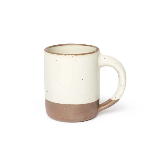 A big sized ceramic mug with handle in a warm off-white glaze featuring iron speckles and unglazed rim and bottom base.